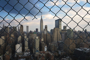 View on the New York city through the hole of steel mesh wire fence. Concept