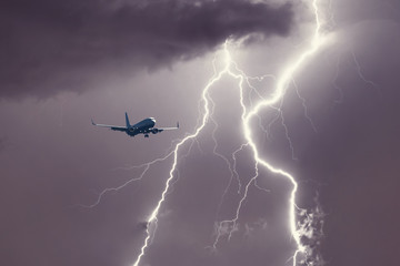 Passenger airplane landing in the stormy weather on the backdrop lightning