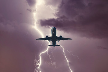 Passenger airplane landing in the stormy weather on the backdrop lightning