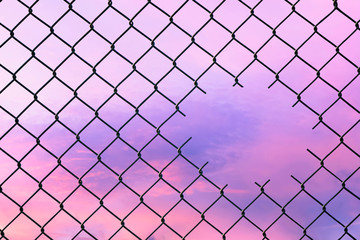 Hole in the center of mesh wire fence on the sky background. Concept of hope and freedom