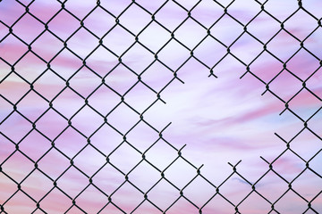 Hole in the center of mesh wire fence on the sky background. Concept of hope and freedom