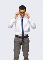 Young afro american businessman with glasses and surprised on isolated background