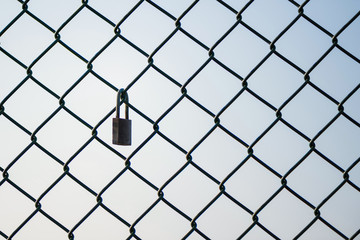 Mesh wire fence with lock on the sky background. Isolated.