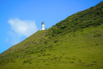 Landscape view at the Bay of Islands: green fields, blue sky and white lighthouse, North Island,...
