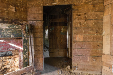 Fototapeta na wymiar Doorway in long forgotten abandoned wood paneled farmhouse