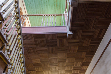 Parquet ceiling above classic wooden staircase leading up to a green wood paneled ceiling in an epic abandoned plantation home