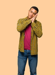 Young afro american man making sleep gesture in dorable expression on isolated background