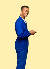Young afro american worker man sending a message with the mobile on isolated background