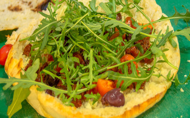 Turkish bread, which when cooked remains hollow inside, garnished with butter, cheese, fresh and dried cherry tomatoes, olives and arugula.