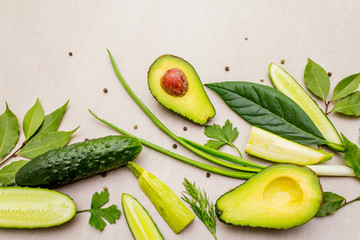 Green vegetables and herbs cooking background. Avocado, avocado leaf, bay leaf, cucumber, zucchini, parsley, dill, green onion feathers, peppers mix. On a stone background, flat lay