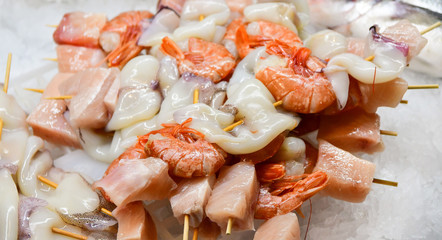 fresh peeled seafood shrimp and squid with pieces of salmon in the ice, Italian market, Italian cuisine. selective focus