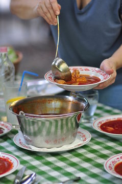 Serving traditional Hungarian and Serbian fish soup cooked with red pepper - Halaszle 