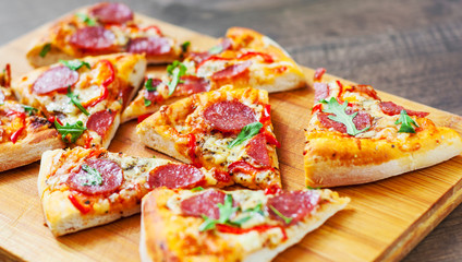 Pepperoni Pizza with Mozzarella cheese, salami, Tomatoes, pepper, Spices and Fresh arugula. Italian pizza on wooden table background