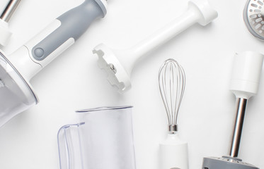 Electric hand mixer. Set of nozzles and  containers for blender on white background. Top view, flat lay.