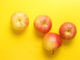 Red apples on yellow background. Autumn still life. Top view.