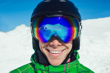 Close up of the ski goggles of a man with the reflection of snowed mountains