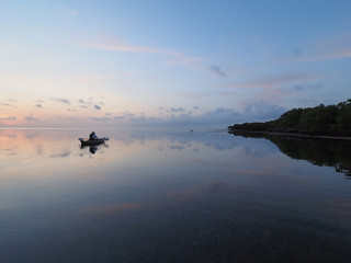 Obraz na płótnie Canvas Kayaker at sunrise on the perfectly still water of Bear Cut off Key Biscayne, Florida.