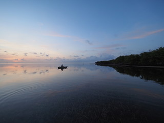 Kayaker at sunrise on the perfectly still water of Bear Cut off Key Biscayne, Florida.