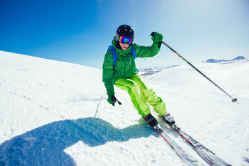 Skier skiing downhill during sunny day in high mountains