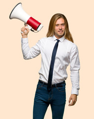 Blond businessman with long hair holding a megaphone on isolated background