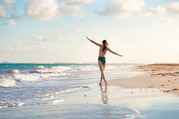 Carefree and happy young brunette woman on the beach in the Mayan Riviera, Mexico.