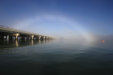 Bright fogbow over the Bear Cut Bridge on a calm foggy morning off Key Biscayne, Florida.