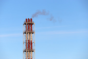 Factory pipes, thin wisp of smoke from chimney on sky background. Concept of industry and ecology, steam plant, environmental friendly, air pollution, heating season, global warming