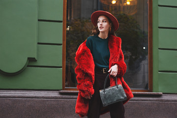  Outdoor fashion portrait of young beautiful confident lady wearing trendy orange faux fur coat,...