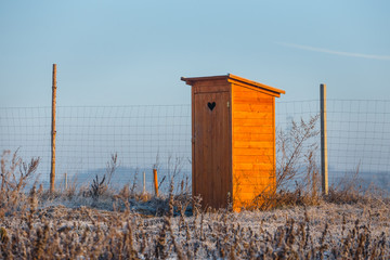 An old wooden toilet building at sunrise