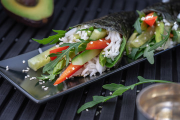 Vegan sushi temaki with rice on a black plate.
