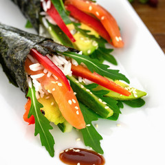 Sushi Temaki on a white plate with soy sauce.