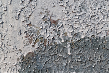 Cracked flakes of old oil paint on the surface of the concrete slab. Pattern of two colors, white and gray. Texture, background or backdrop. The result of environmental impact.