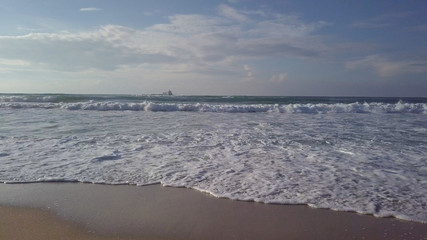 Surf at costline with parked sea tanker