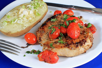 Overhead View of Pork Chop and Seared Tomatoes with Baked Potato