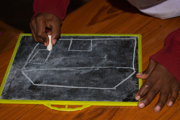 In a primary school, a picture is being drawn on a slate with chalk.