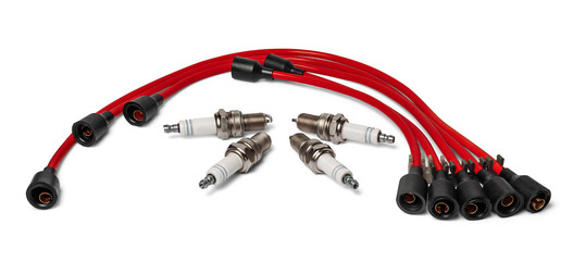 Four spark plugs and red wires of a high pressure are isolated on white background. Car parts.