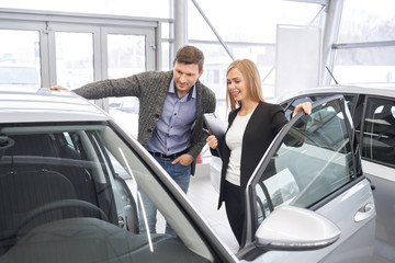 Fototapeta na wymiar Female car dealer showing automobile to potential buyer.