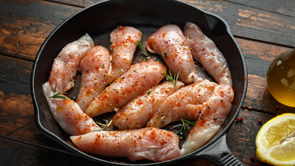 Raw chicken breast mini fillets in rastic cast iron skillet, frying pan with herbs and sea salt