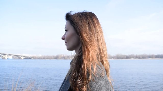 Side view of the portrait of a brunette girl near the river.