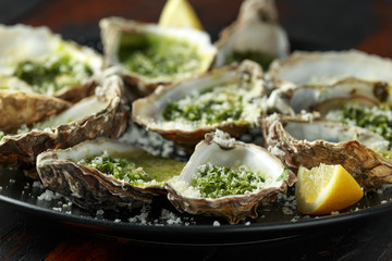 Grilled oysters with Parsley and garlic butter served with parmesan and lemon wedges