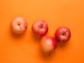 Red apples on orange background. Autumn still life. Top view.