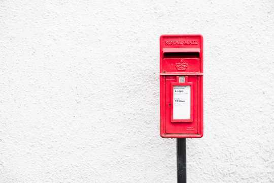 Red post mail box against plain white wall background