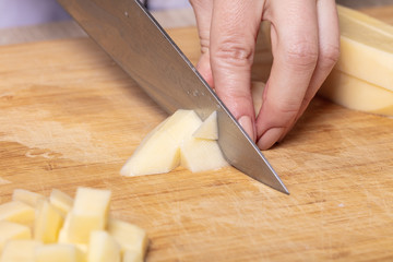 cook cuts potatoes on a wooden board