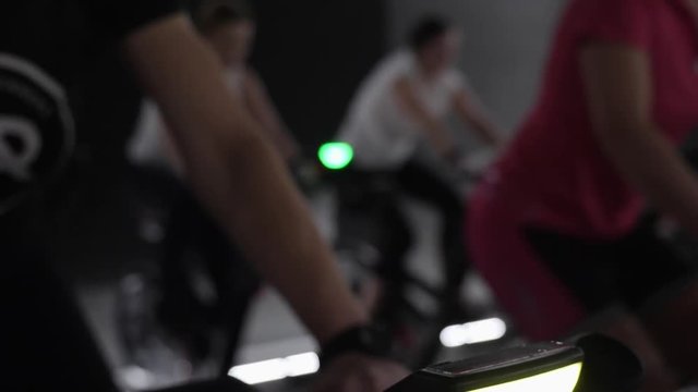 Young caucasian girls working out in spinning studio on stationary bicycles. Cardio training