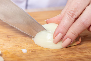 cook cuts onion on a wooden board