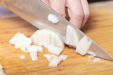 Fototapeta na wymiar cook cuts onion on a wooden board