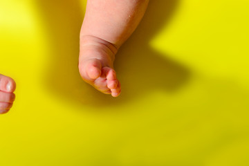 Baby legs on a yellow background, small leg of a newborn baby.