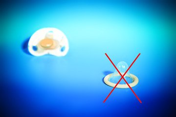 The crossed out condom with a pacifier, the concept of a healthy child, for birth, against - contraception.