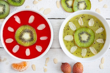  Smoohtie bowls z mrożonych truskawek i kiwi ozdobione owocami i płatkami migdałów