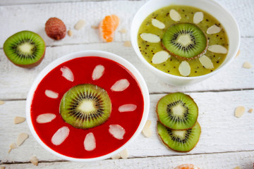 Smoohtie bowls z mrożonych truskawek i kiwi ozdobione owocami i płatkami migdałów